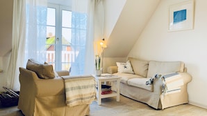 Een gezellige woonkamer met twee beige banken, een salontafel en een lamp.