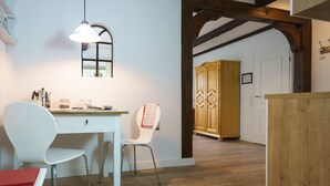 Eine Küche mit einem weißen Tisch, zwei weißen Stühlen, einer Pendelleuchte und Holzschränken.