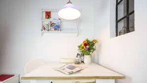 Ein Essbereich mit einem weißen Tisch, einer Hängeleuchte, einem Bücherregal und einer Vase mit Blumen.