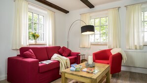 Een woonkamer met een rode bank, een houten salontafel en een vloerlamp.