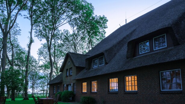 A traditional brick house with a steeply pitched roof, multiple windows, and a well-maintained lawn. - Ferienwohnung "haubarg Windschuur 4" in Welt für 2 Personen (Welt)