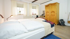 A bedroom with a large bed, wooden wardrobe, and a desk with a chair. - Ferienwohnung "haubarg Windschuur 4" in Welt für 2 Personen (Welt)