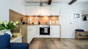 A modern kitchen with white cabinets, a built-in oven, and a wooden countertop. - Ferienwohnung "haubarg Windschuur 4" in Welt für 2 Personen (Welt)