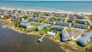 Vista aérea de una zona residencial costera con casas, un muelle y una playa.