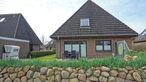 A residential house with a tiled roof, brick walls, and a stone wall in the foreground. - Appartement "rochelsand EG" in Tating für 1-3 Personen (Tating)