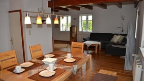 A dining area with a wooden table set for four, a sofa, and a radiator in the background. - Rosenkate in Garding: 130 m² space for 5 people (Garding)