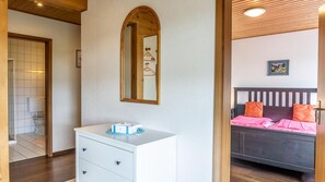Quarto com uma cama, mesa de cabeceira, espelho e porta de acesso a um banheiro.