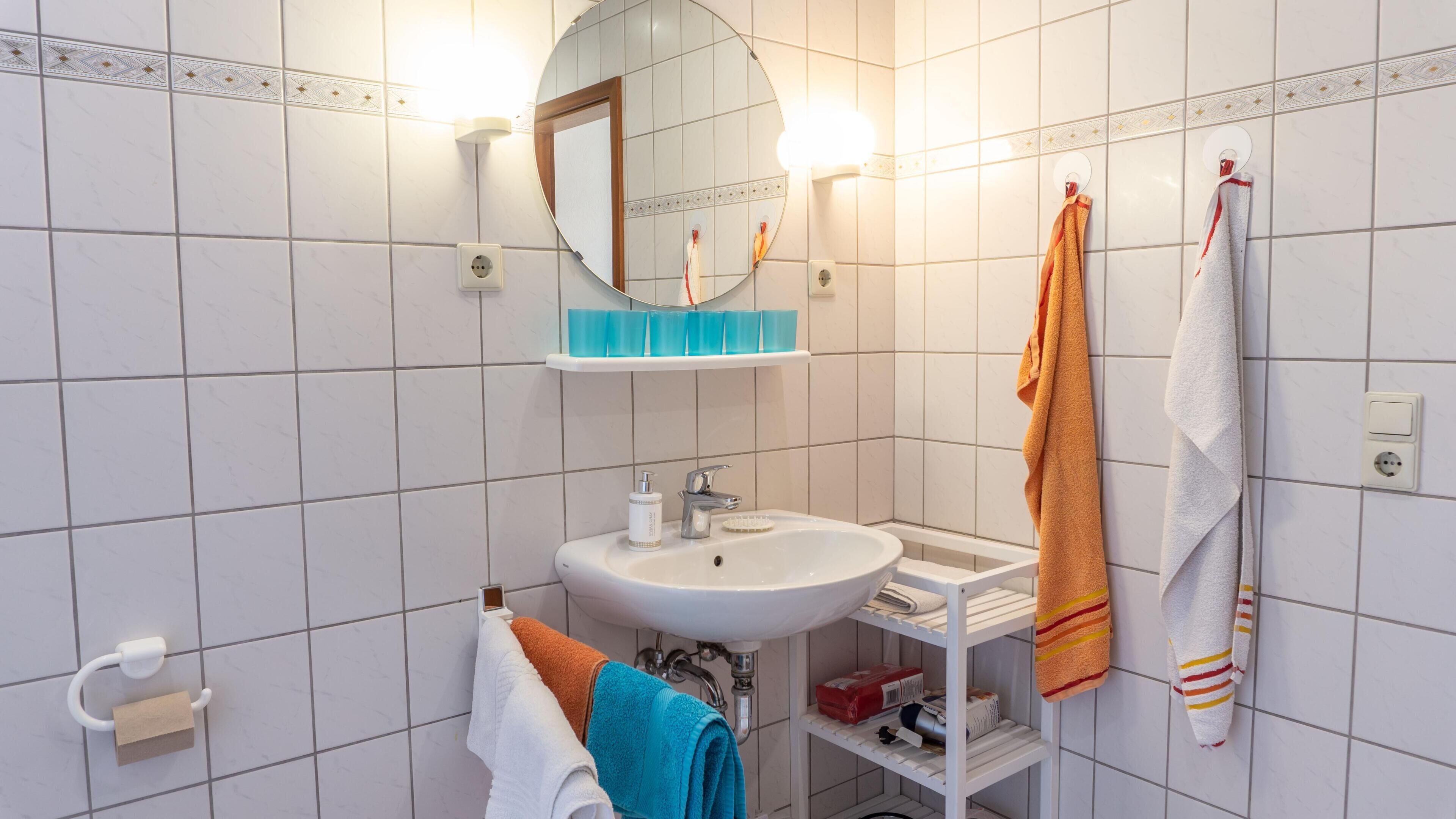 A bathroom with a white sink, mirror, and towel rack.