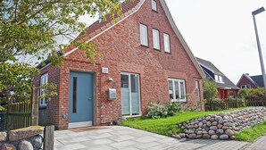 A red brick house with a blue door, a small garden, and a stone wall.