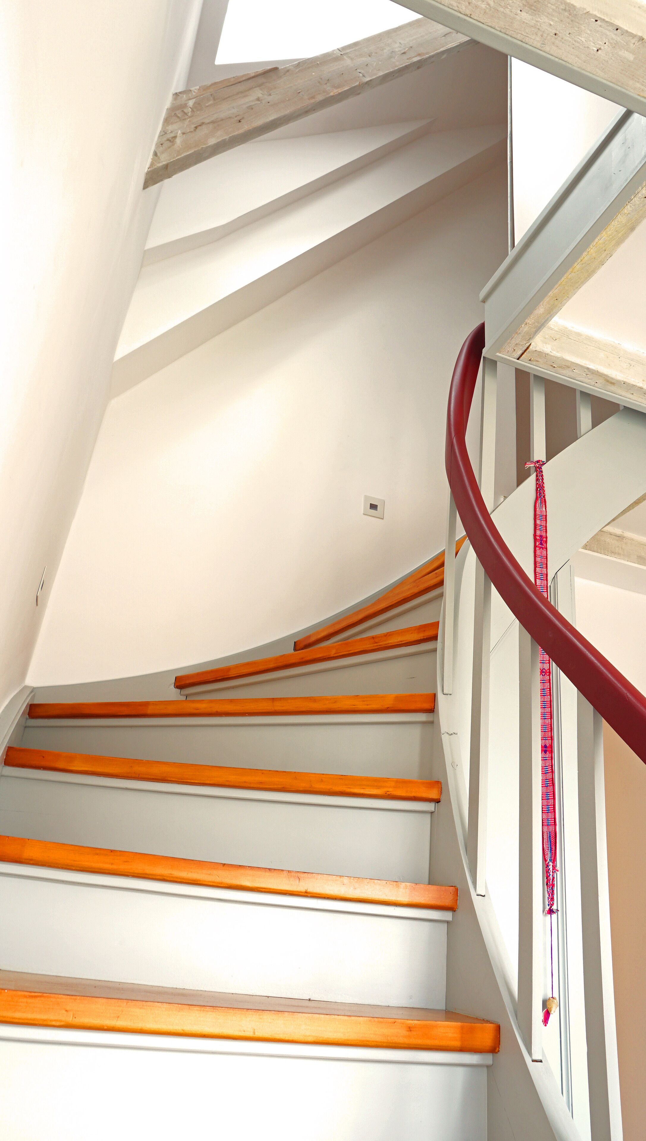 Una escalera con barandillas de madera y una barandilla roja.