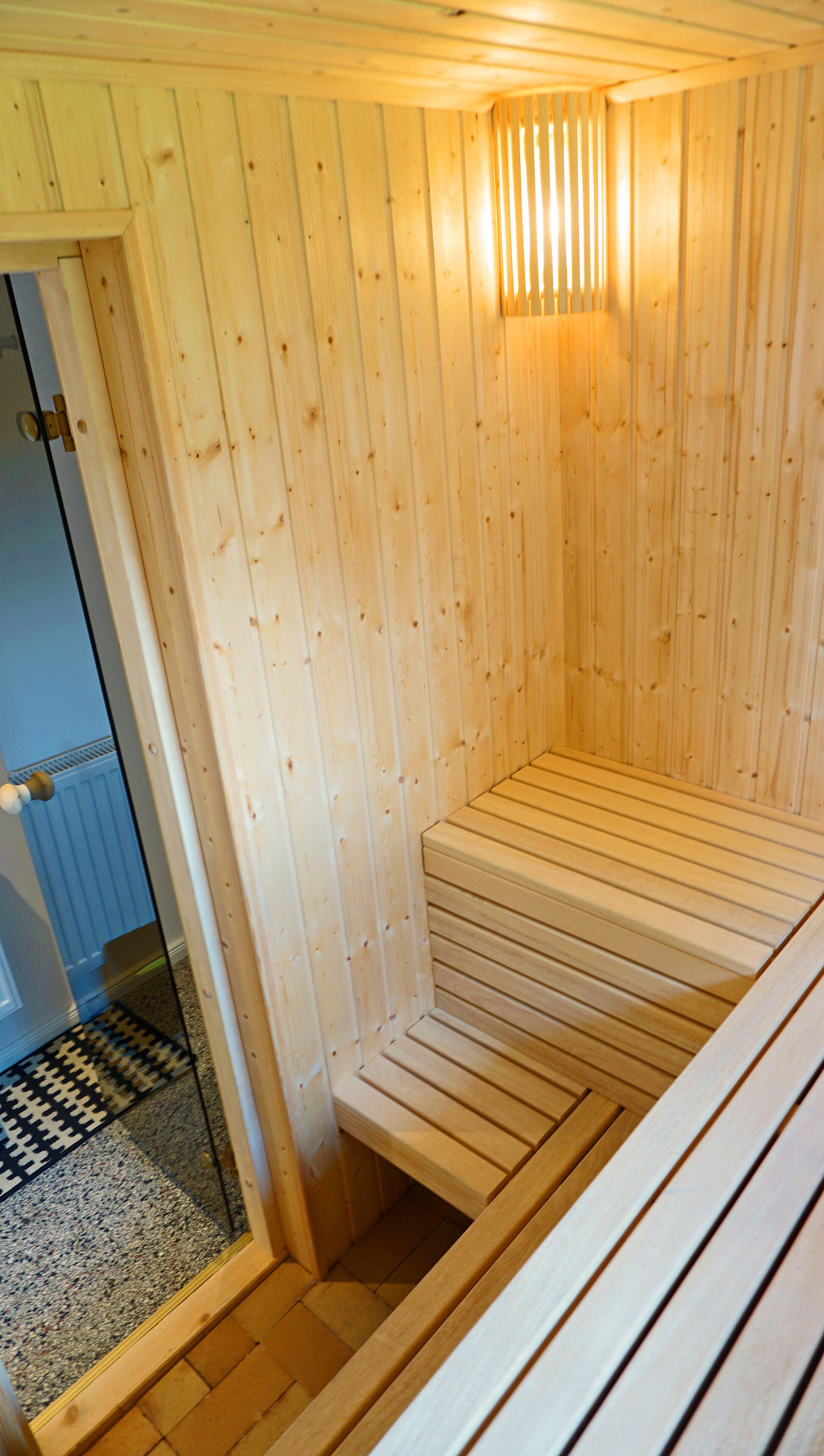 Uma sauna com bancos de madeira e porta de vidro.