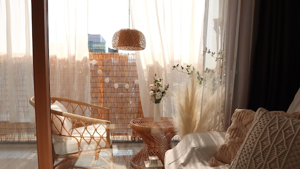 A cozy room with a large window, wicker furniture, and a view of a cityscape. - Morning Madrid (Jeju City)
