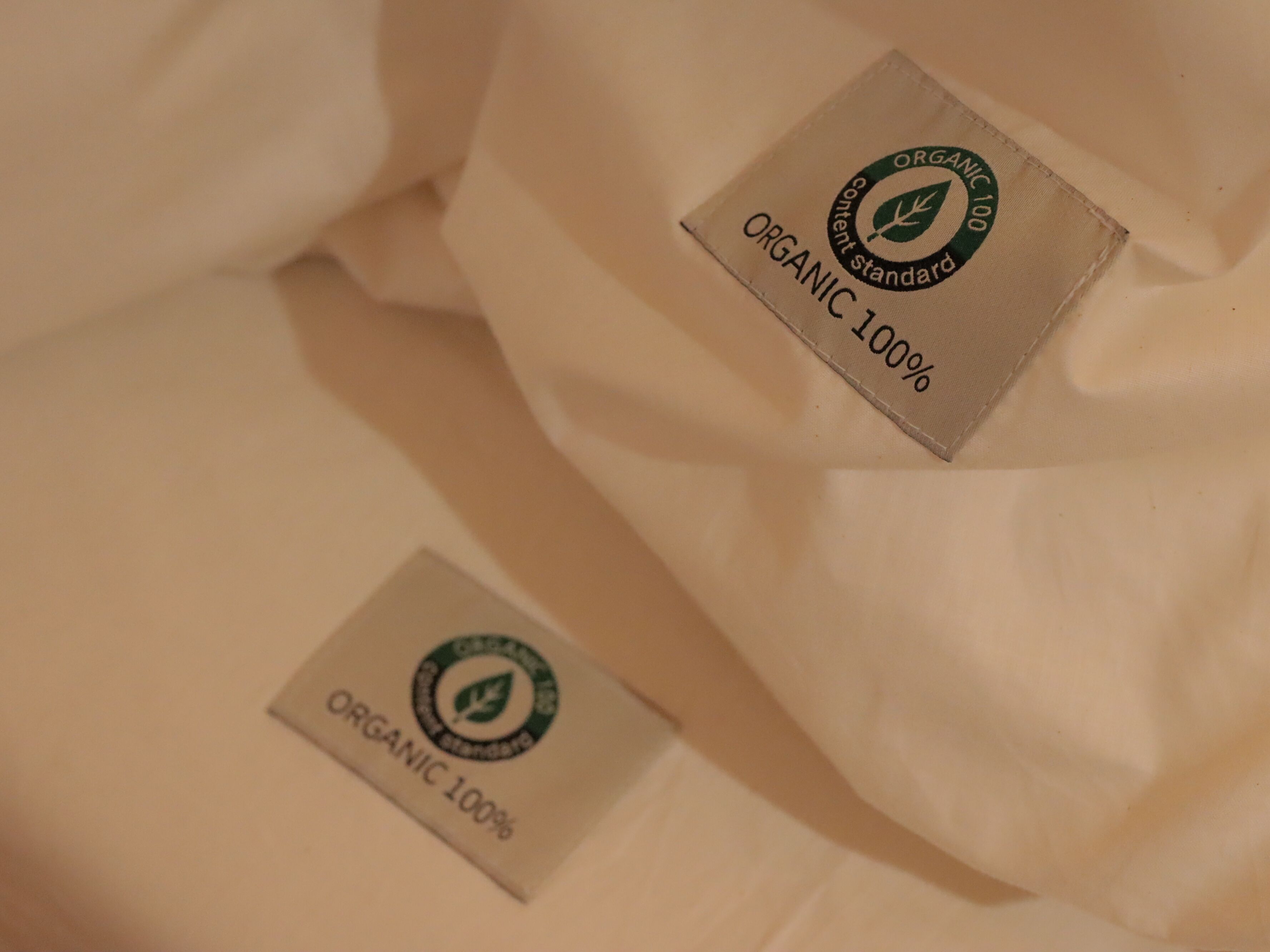 A close-up of fabric with two labels indicating 'ORGANIC 100%'.