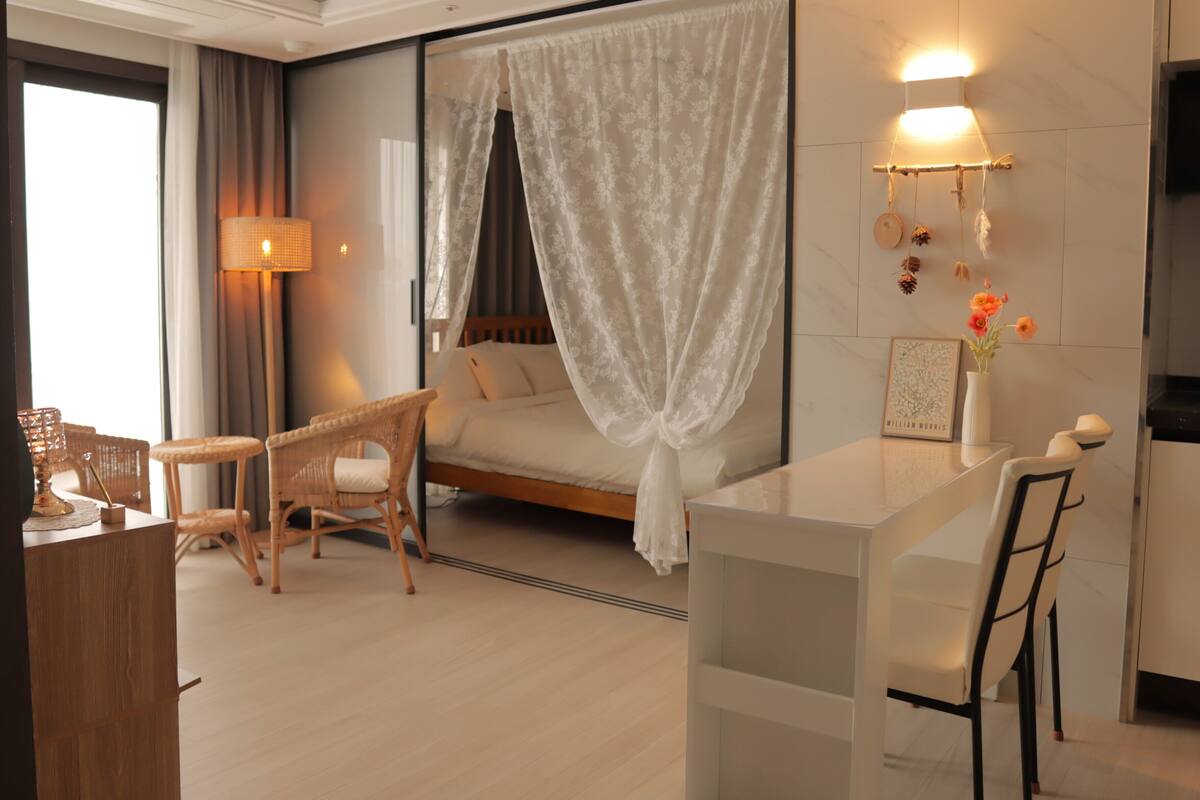 A modern hotel room with a bed, a desk, and a chair.