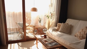 A cozy living room with a sofa, a coffee table, and a wicker chair. - Morning Madrid (Jeju City)
