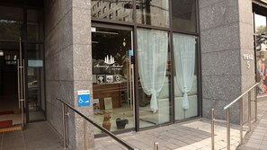 A modern building entrance with a glass door, a ramp, and a sign indicating a pet zone. - Morning Madrid (Jeju City)