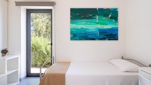 Een slaapkamer met een bed, een raam, een deur en een schilderij aan de muur.