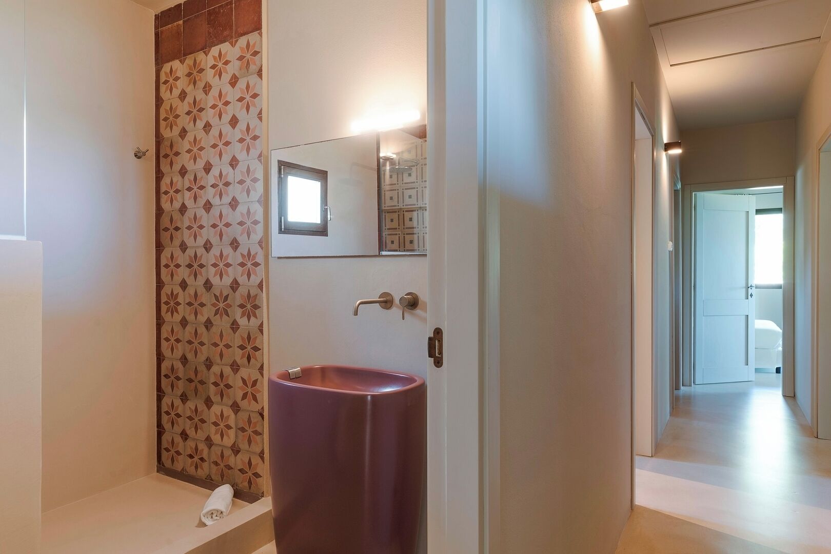 A bathroom with a patterned tile wall, a purple sink, and a mirror above it.