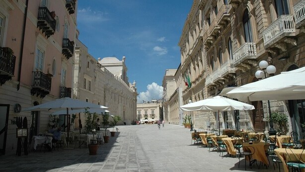 A cobblestone street lined with outdoor cafes, historic buildings, and a clear blue sky. - Casa Dei Nonni - Apartment in Syracuse (Syracuse)