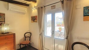 A room with a wooden dresser, a chair, a door with a view to the outside, and a painting on the wall. - Casa Dei Nonni - Apartment in Syracuse (Syracuse)