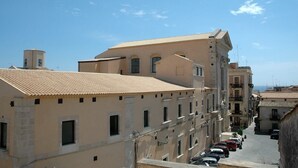 A narrow street with buildings featuring terracotta roofs and arched windows. - Casa Dei Nonni - Apartment in Syracuse (Syracuse)