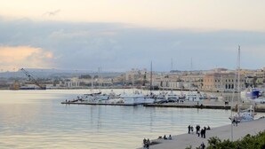 A marina with boats docked, a crane, and buildings in the background. - Casa Dei Nonni - Apartment in Syracuse (Syracuse)