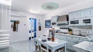 Una cocina moderna con armarios blancos, una mesa de comedor con sillas y un colgador para ollas.