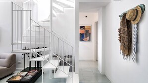 Un interior moderno con una escalera blanca, un sofá y una mesa de centro.