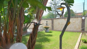 A garden with a fountain, a stone wall, and a variety of plants. - Villa Trapezio with private pool and tennis court (Quartu Santa Elena)