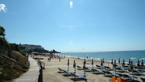 A beach with rows of sun loungers and umbrellas, a pathway leading to the beach, and a building in the background. - Casa Francesca 2 - Private villa with two terraces (Sperlonga)