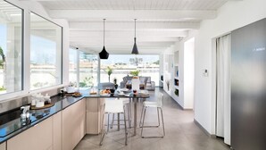 Una cocina moderna con una isla grande, taburetes de bar e iluminación colgante.