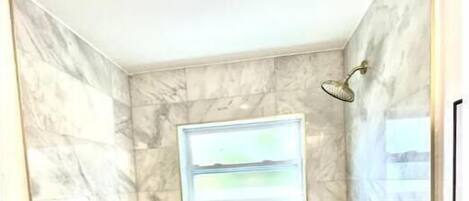 A bathroom with a marble wall, a bathtub, and a framed picture.