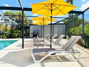 A poolside area with sun loungers and yellow umbrellas.