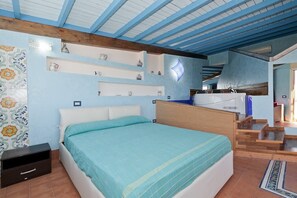 Ein Schlafzimmer mit Bett, Nachttisch, einer Kommode mit Dekoration und einer Treppe zu einer oberen Ebene.