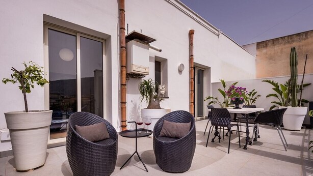 Une terrasse extérieure avec des chaises en osier, une table et des plantes en pot.