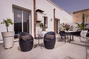 An outdoor patio with wicker chairs, a table, and potted plants.