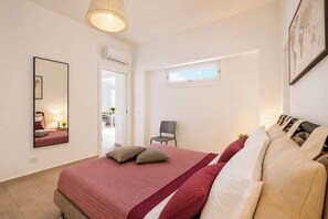 Une chambre à coucher avec un lit, une chaise, une fenêtre et un miroir.