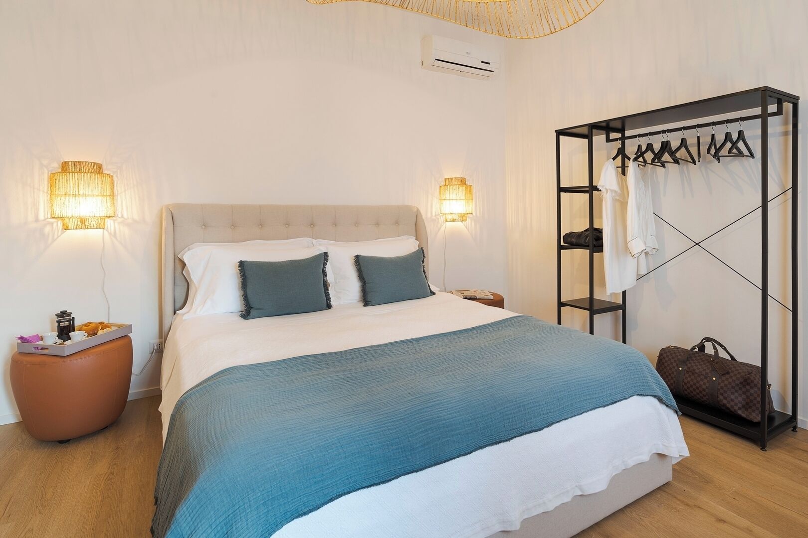Habitació d'hotel ordenada amb llit, taules de nit, un armari i una barra de roba.