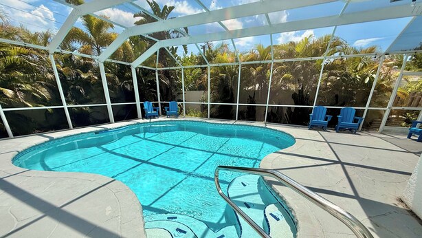 Una piscina con diseño único, rodeada de una zona techada con sillas.