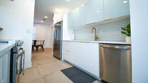 Una cocina moderna con armarios blancos, lavavajillas de acero inoxidable y salpicadero de azulejos.