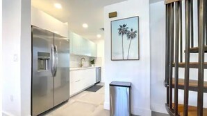Una cocina moderna con electrodomésticos de acero inoxidable, armarios blancos y un pequeño cubo de basura.
