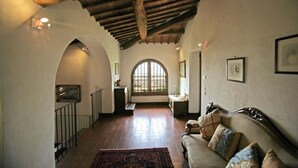 Un passadís ampli amb un sostre alt, portes arqueades i un gran finestral que deixa entrar llum natural.