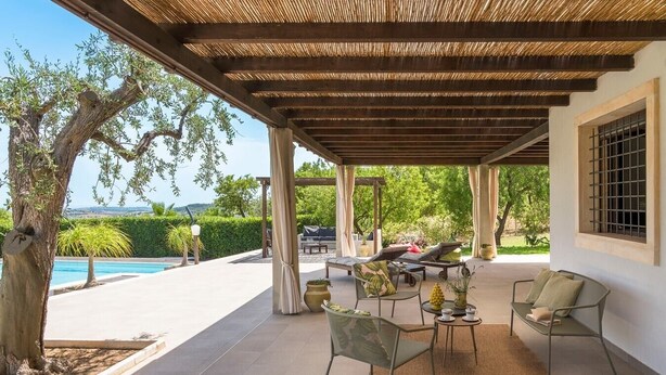 A covered outdoor seating area with chairs and a table, a pool in the background, and a view of the landscape. - Villa Raggera - Private villa with pool near Noto (Ispica)