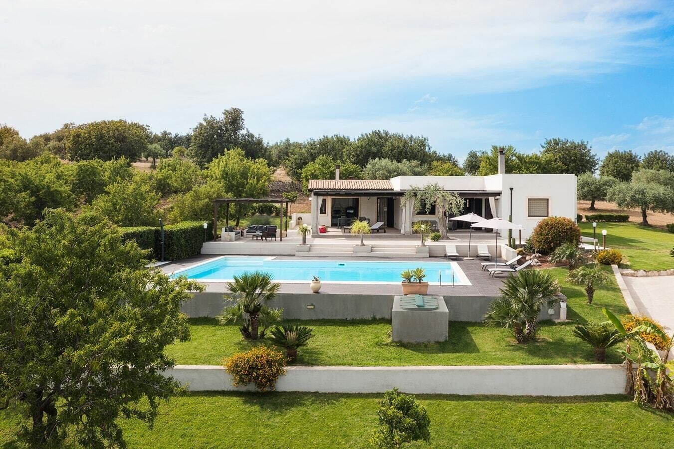 Uma casa moderna com piscina, área de estar externa e vegetação exuberante.