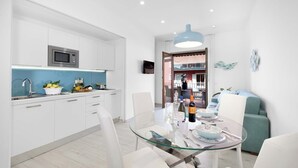 Een moderne keuken met witte kasten, een inbouwmagnetron en een blauw aanrecht.