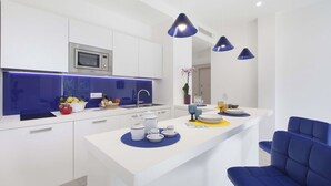 Een moderne keuken met witte kasten, een ingebouwde magnetron en een centraal eiland met blauwe placemats.