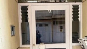Eine weiße Tür mit der Nummer 38, einem kleinen Fenster und einer Metallhand. 