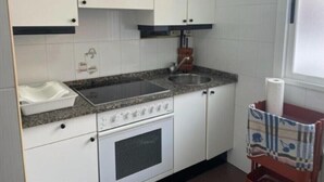 Eine Küche mit weißen Schränken, einer Granit-Arbeitsplatte, einem Edelstahl-Spülbecken und einem eingebauten Backofen.
