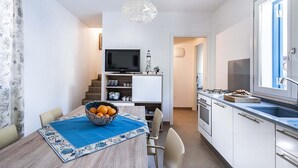 Eine kleine Küche mit Essbereich, einem Fernseher und einer Treppe zu einem weiteren Raum.