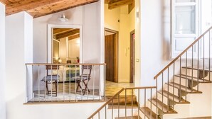 Una escalera con barandillas de madera que conduce a una habitación con una cama, una mesa y sillas.